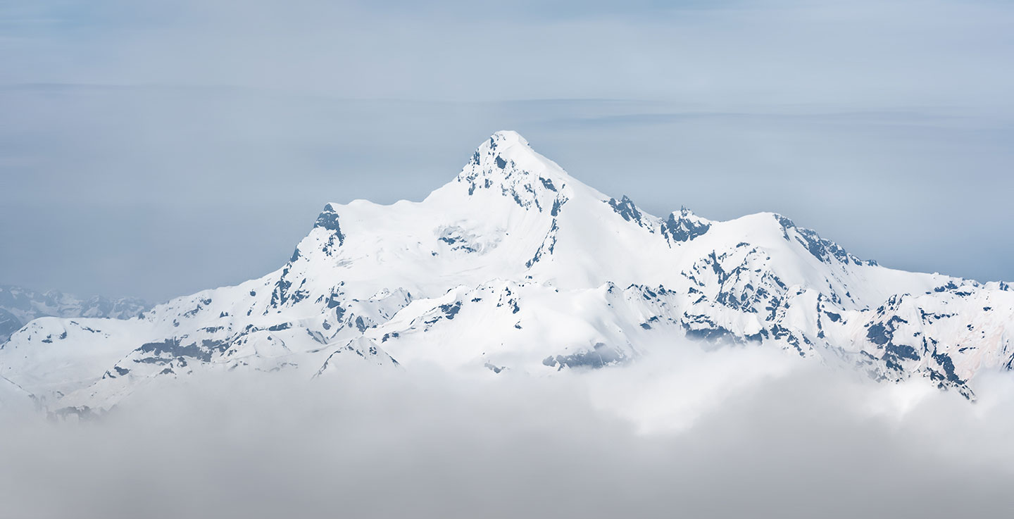 Snow-covered mountain peak rising above the clouds, symbolizing reaching new heights and gaining clarity through Vistage's business resources.